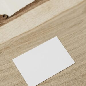 Empty white business card on wooden desk